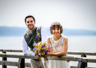 Brautpaar am Ammersee, Hochzeitsfoto mit Blumen am Steg, Diessen am Ammersee, romantisch.