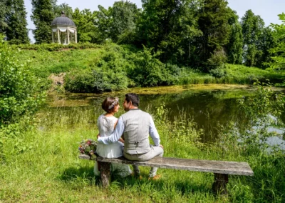 Brautpaar am Ammersee, romantisch im Schacky Park auf einer Bank am Seeufer, umgeben von Natur.
