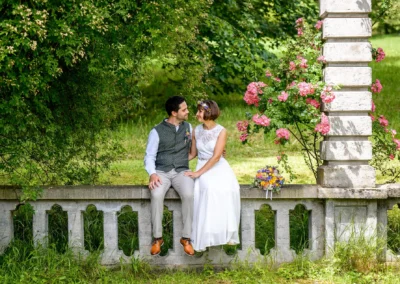 Brautpaar am Ammersee im Schacky Park sitzend, umgeben von Blumen und Natur, romantische Hochzeitsfotos.