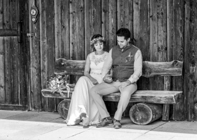 Brautpaar auf einer Holzbank am Ammersee, Schacky Park, romantische Hochzeitsfotografie.