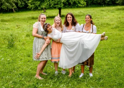 Brautparade bei Hochzeitsfeier in Beuern, Türkenfeld - Freunde tragen die Braut auf der Wiese.