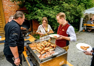Hochzeitsfeier in Beuern mit Gästen am Grillbuffet, Türkenfeld nahe München. Rustikale Atmosphäre im Freien.