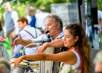Musiker auf Hochzeit in Seehaus Riederau, mit Akkordeon und Mikrofon, feiern das Brautpaar in Diessen am Ammersee.