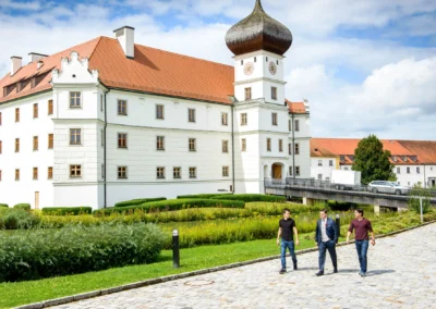 Drei Personen spazieren vor Schloss Hohenkammer, Ort fuer Hochzeitsfotos oder Hochzeitsportraits.