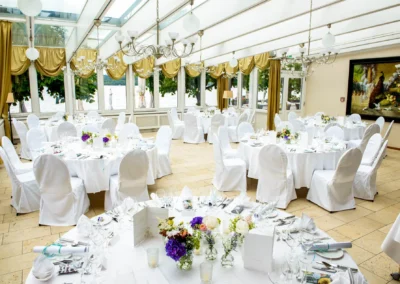 Elegante Hochzeitsdekoration in Starnberg mit runden Tischen, weissen Tischdecken und blumigen Arrangements.