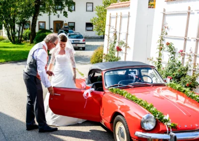 Brautpaar bei kirchlicher Trauung in Schonstett, das zu einem geschmückten Oldtimer für die Hochzeitsreportage geht.