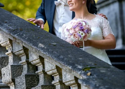 Brautpaar-Foto am Friedensengel in München, romantische Hochzeitsreportage mit Blumenstrauss und Lächeln.
