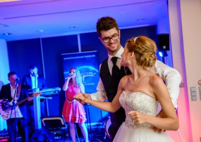 Brautpaar tanzt bei der Hochzeit im Hotel Aiterbach am Chiemsee, Band spielt im Hintergrund.