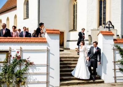 Brautpaar verlaesst Kirche in Schonstett, Hochzeitsreportage mit Gaesten und Seifenblasen, festlicher Moment.