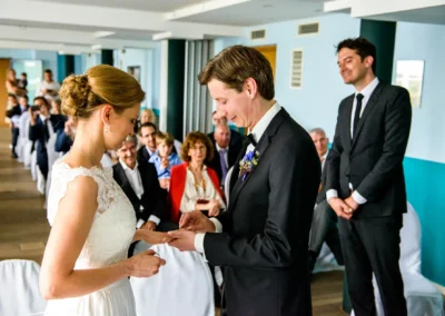 Hochzeit in Starnberg: Brautpaar tauscht Ringe waehrend der Trauung vor Gaesten, Hochzeitsreportage von Fotografin.