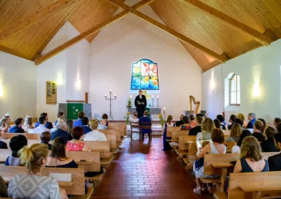 Hochzeitszeremonie in der Martin-Luther-Kirche Fischbachau, Gaeste sitzen in den Kirchenbaenken.