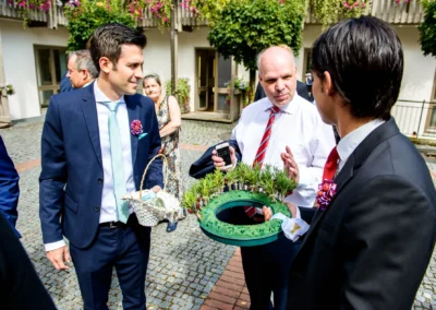 Hochzeitsgaeste bei freier Trauung auf Schloss Hohenkammer, festlich gekleidet, in Gespraech vertieft.