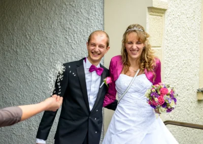 Brautpaar lacht beim Reiswurf nach Trauung, Standesamt Schleissheim, Hochzeitreportage nördlich von München.