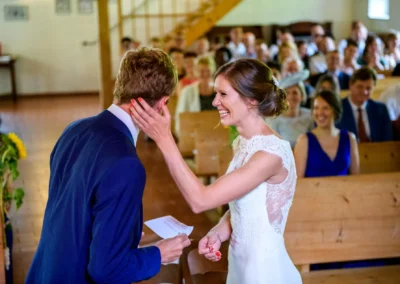 Brautpaar lacht bei Trauung in Martin-Luther-Kirche, Fischbachau, umgeben von Gaesten, Hochzeitreportage.