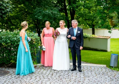 Braut mit Blumenstrauss bei freier Trauung auf Schloss Hohenkammer, begleitet von drei Personen in eleganter Kleidung.