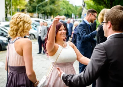 Gäste bei kirchlicher Hochzeit in Giesing, lachen und begrüßen sich auf Hochzeitsreportage in München.