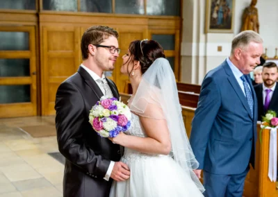 Brautpaar bei kirchlicher Trauung in Sankt-Franziskus, Giesing. Hochzeit mit Blumenstrauss und emotionsvollem Moment.