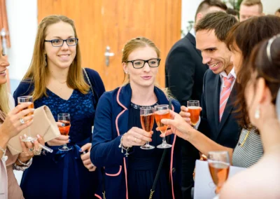 Gäste bei Hochzeitsfeier in Dachau stoßen mit Sekt an. Festliche Trauung und Reportage von Zieglerbraeu.