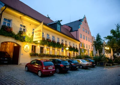 Hochzeitsfeier im Zieglerbraeu Dachau bei Abenddaemmerung, mit beleuchtetem Hotel und parkenden Autos.