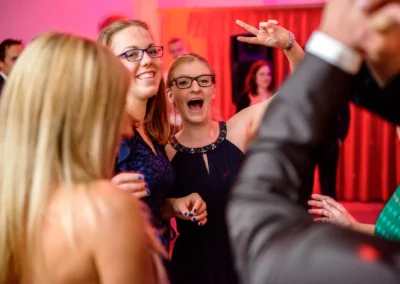 Feierliche Hochzeitsreportage in Dachau, froehliche Gaeste tanzen und lachen auf der Hochzeitsparty.