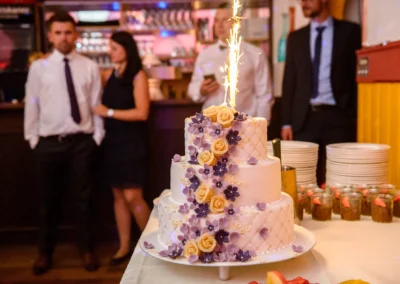 Hochzeitsfeier in Dachau: Hochzeitstorte mit Blumen und Wunderkerze bei Zieglerbraeu, elegante Trauungsszene.