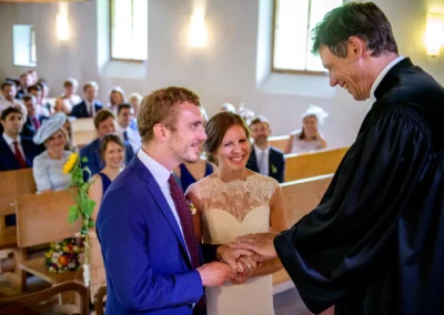 Trauung in der Martin-Luther-Kirche Fischbachau, Brautpaar beim Ja-Wort mit Gaesten im Hintergrund.