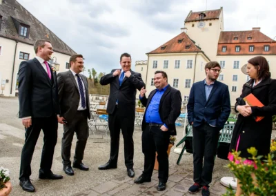 Gäste lachen bei Hochzeit vor Schloss Seefeld. Hochzeitsreportage westlich von München in entspannter Atmosphäre.