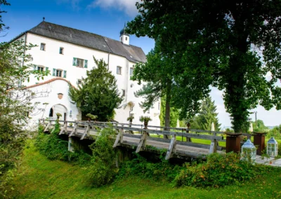 Schloss Amerang Hochzeit Fotografie: Schlossansicht mit Bruecke und Park, ideal fuer Trauungsfeier im Chiemgau.