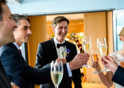 Gäste stoßen bei Hochzeit am Starnberger See mit Sektgläsern an. Fröhliche Trauung in Berg am Starnberger See.