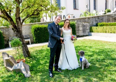 Brautpaar bei standesamtlicher Trauung in Poegging am Starnberger See mit Hund im sonnigen Garten.