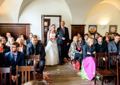 Braut in weissem Kleid betritt bei Trauung Schloss Seefeld, Gaeste sitzen erwartungsvoll im Saal