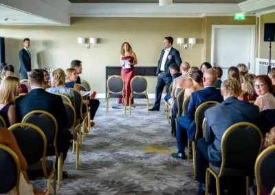 Hochzeitsfeier im Hilton Tucherpark, München: Gäste sitzen, Redner vorne. Eventfotografie für Trauung und Feier.