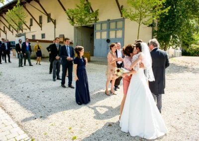 Brautpaar begruesst Gaeste bei Hochzeit im Schloss Amerang. Hochzeitsreportage Chiemgau im Freien mit eleganter Kulisse.