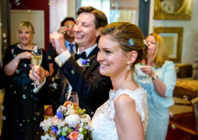 Brautpaar feiert Hochzeit mit Freunden und Sekt, aufgenommen bei einer Trauung in Starnberg. Hochzeitsreportage.