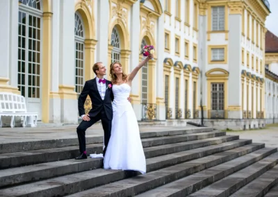 Brautpaar posiert auf Treppe vor Schloss Schleissheim, Hochzeitsshooting nördlich von München, freudiger Moment.