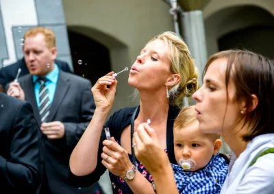 Gaste pusten Seifenblasen auf Hochzeitsfeier im Schloss Pertenstein. Hochzeitsreportage mit Kind und Freude.