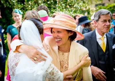 Braut bei Hochzeit im Schloss Amerang umarmt lachende Gaeste, Hochzeitsreportage im Chiemgau, freudige Trauung.