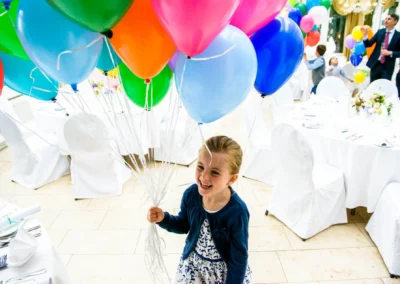 Mädchen mit Luftballons bei Hochzeit in Starnberg, fröhliches Ereignis in Hochzeitsreportage, dekorierte Tische.