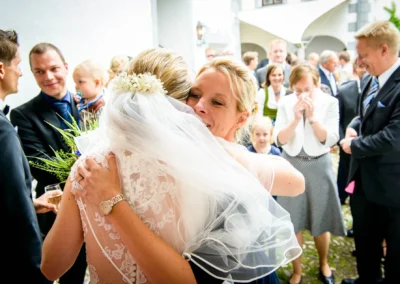 Braut umarmt Gast bei einer Hochzeitsfeier, Freude und Emotionen im Schloss Pertenstein. Hochzeitsreportage Traunreut.