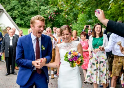 Hochzeitspaar in Fischbachau, Konfetti fliegt, festliche Stimmung vor Martin-Luther-Kirche.