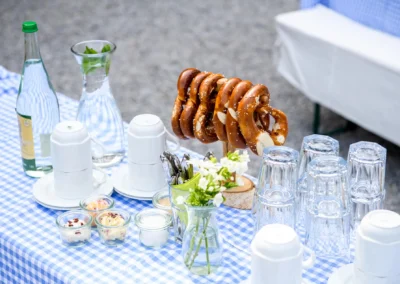 Hochzeit im Hasenoehrlhof, Geitau: Brezeln und Glaeser auf blau-weiss karierter Tischdecke als Buffet-Dekoration.