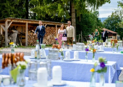 Hochzeitsfeier im Hasenoehrlhof, Geitau: Gaeste in Tracht, dekorierte Tische mit Brezeln und Blumen.
