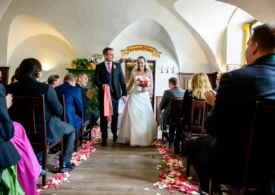 Brautpaar bei Trauung in Schloss Seefeld, umgeben von Gaesten, mit Rosenblaettern auf dem Boden. Hochzeitsreportage.