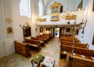 Innenaufnahme einer Kirche bei Hochzeit in Aufhausen mit geschmueckten Baenken und Kronleuchtern, perfekte Trauungsszene.