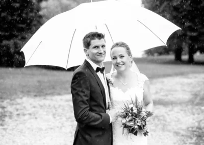 Brautpaar unter Regenschirm bei Hochzeit im Schloss Pertenstein, Traunreut, festgehalten von Hochzeitsfotograf.