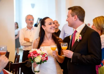 Brautpaar bei der Hochzeit im Schloss Seefeld, laechelnd mit Getraenken in der Hand, festliche Atmosphaere.