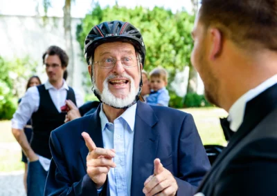 Hochzeitsszene in St. Martin Germering: Gast mit Helm unterhaelt sich herzlich bei der kirchlichen Feier.
