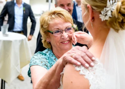 Braut im Spitzenkleid wird liebevoll von aelterer Dame beruehrt. Hochzeit auf Schloss Hohenkammer. Hochzeitsreportage.