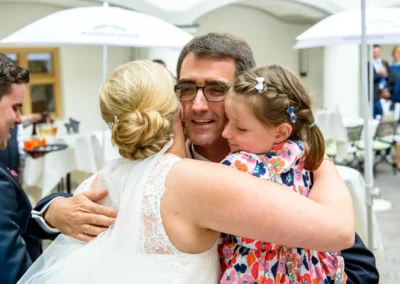 Braut umarmt Mann und Kind bei Hochzeit auf Schloss Hohenkammer. Hochzeitsreportage mit emotionalen Momenten.