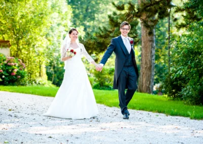 Brautpaar spaziert Hand in Hand bei Hochzeit im Schloss Amerang. Natuerliche Hochzeitsreportage im Freien.